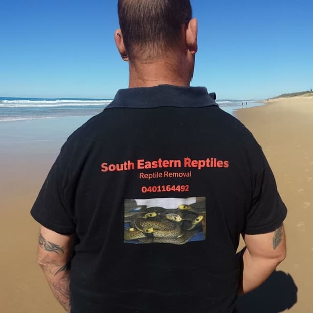 Robert at beach showing off snake catcher business shirt